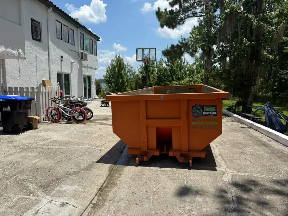 Roll-off dumpster placed in a backyard with lawn protection