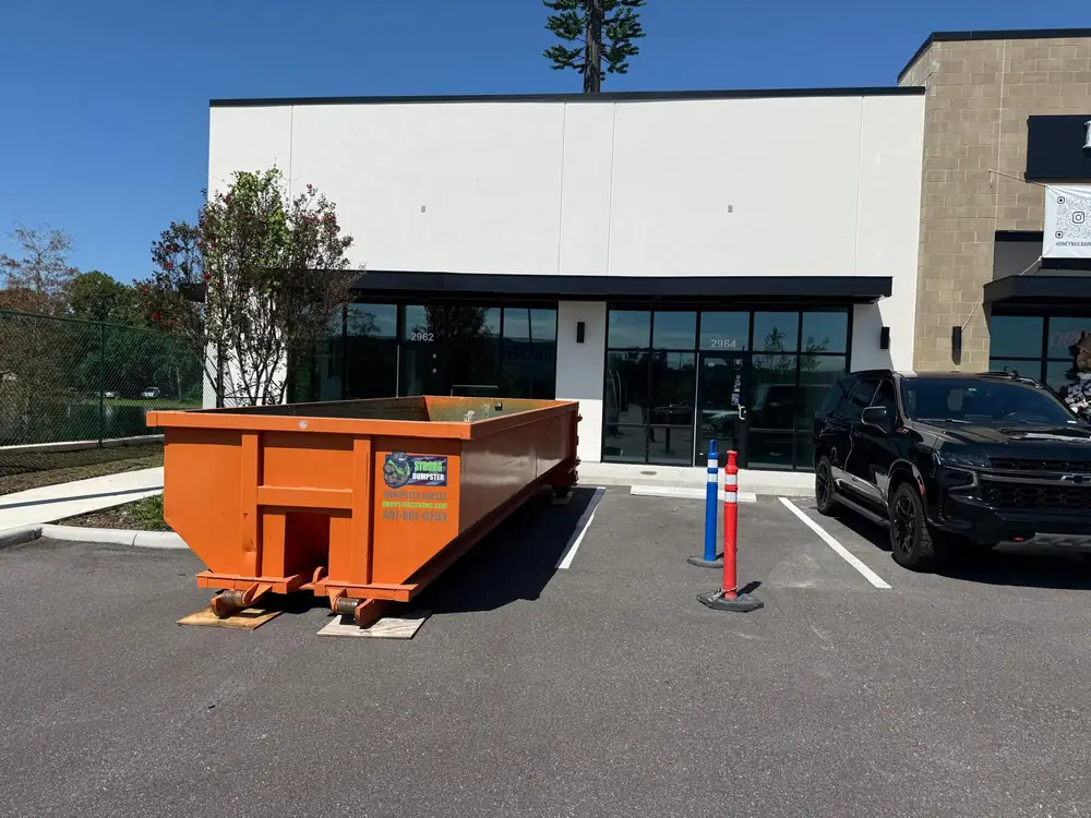 Commercial dumpster rental at an Orlando storefront with protective boards under the wheels