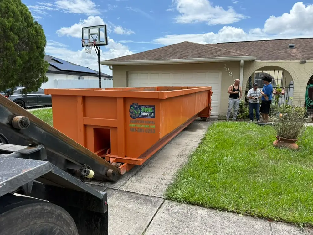 Dumpster Strong truck delivering a roll-off dumpster to a family home in Kissimmee FL