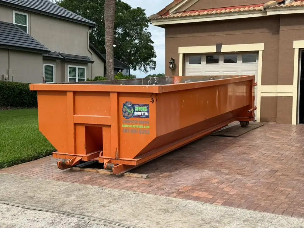 Dumpster Strong roll-off on a brick paver driveway in Dr. Phillips FL with protective boards