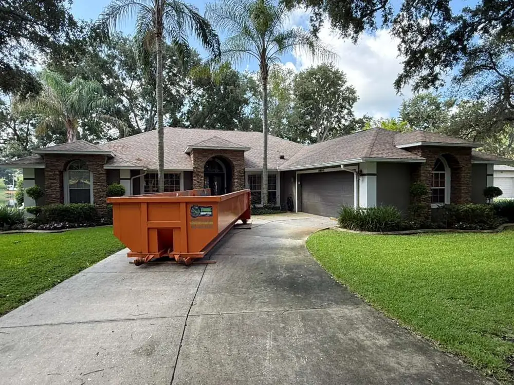 Dumpster Strong roll-off dumpster on a large Lake Mary FL home driveway lined with palms, residential renovation cleanout