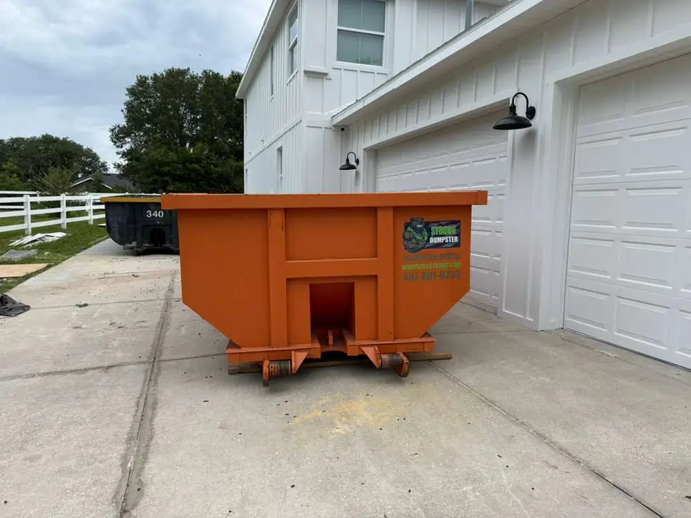 Dumpster Strong roll-off dumpster on an Ocoee FL home driveway beside a two-car garage, residential renovation