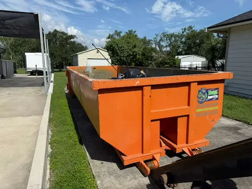 Loaded 20-yard Dumpster Strong roll-off dumpster on a residential side yard concrete pad in Windermere FL, mid-cleanout, HOA-compliant placement