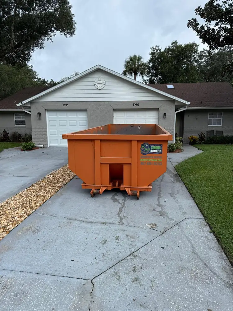 Household dumpster on a duplex driveway for a Kissimmee-area rental turnover cleanout