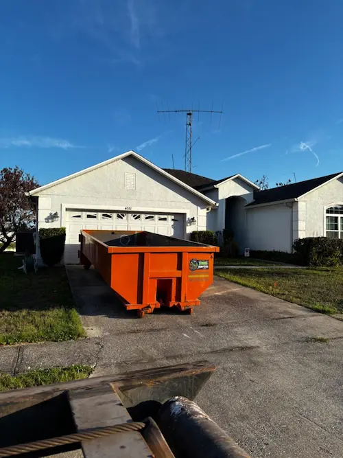 30 yard orange roll-off dumpster on a paver driveway in Oviedo FL