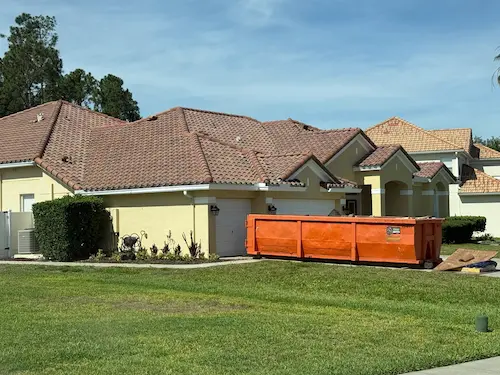 Orange Dumpster Strong roll-off dumpster on an Oviedo FL home driveway