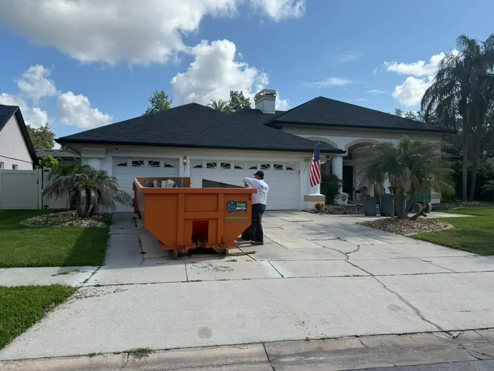 Roofing dumpster loaded with black architectural shingles from a full tear-off, typical of Winter Garden FL reroof season