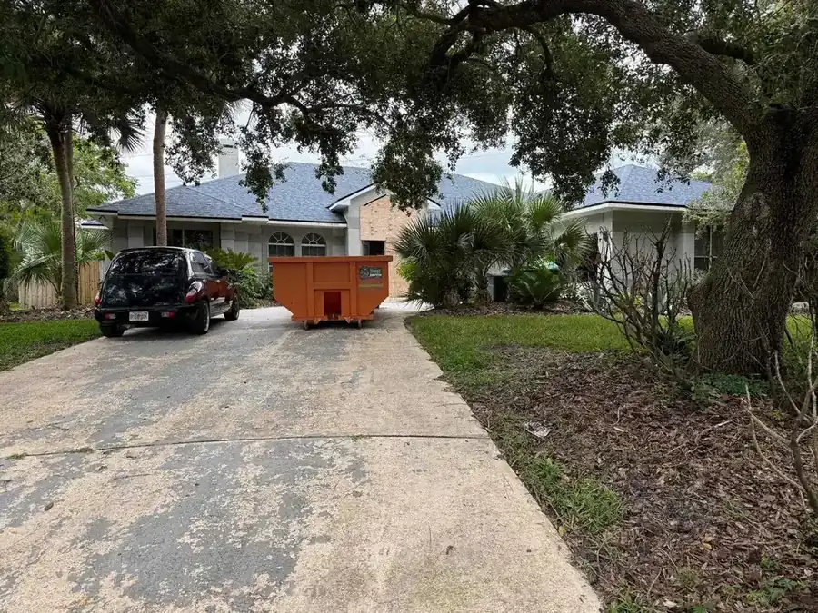 Roll-off dumpster catching shingle debris during a roof replacement, the storm-season tear-off setup Dumpster Strong runs for Oviedo FL homes